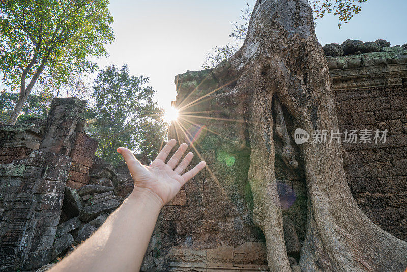 落日余晖中，人的手伸向太阳，吴哥窟古寺、古遗址。能源人环境旅游理念。Ta Prohm，暹粒，亚洲。